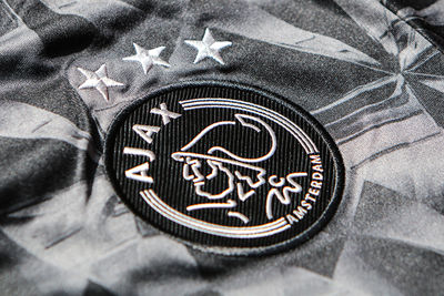 Het Ajaxlogo in zilveren stiksels op een zwart embleem. © Ajax Life