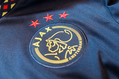 Het logo is goud, terwijl de sterren een rode kleur hebben. © Ajax Life